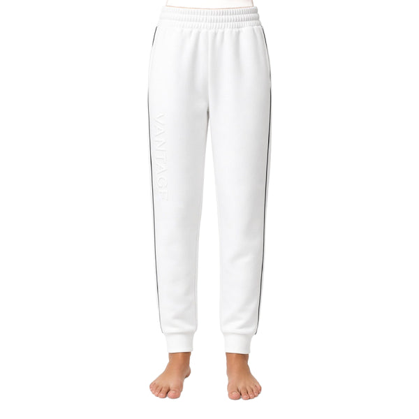 White sweatpants with a subtle tonal vertical logo on the left leg and thin dark side stripes, shown on a model from the waist down against a white background.