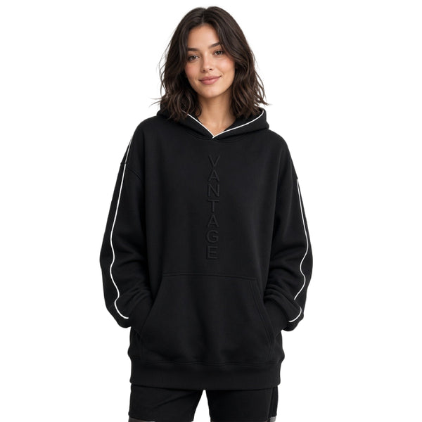A woman wearing a black pullover hoodie with white piping along the hood and sleeves, featuring a vertical 'VANTAGE' logo on the chest, set against a plain white background.